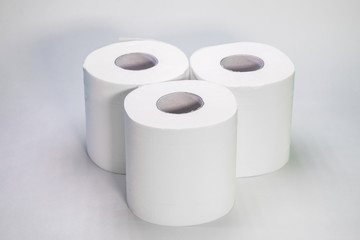 Three rolls of toilet paper stand on a white background