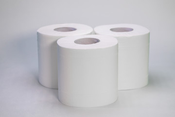 Three rolls of toilet paper stand on a white background