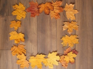 Abstract frame on a brown wooden background with the use of autumn yellow leaves