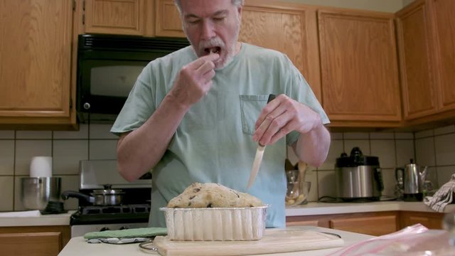 A mature man trying his hand at homemade bread making during stay at home mandates due to COVID19 pandemic smiles at the camera.
