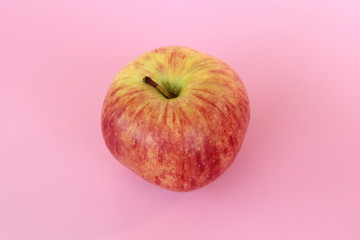 Red yellow apple on a pink background. Juicy ripe beautiful fruit.