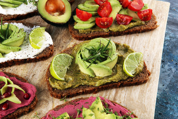 Avocado sandwich. Variation of healthy rye breakfast sandwiches with avocado and toppings like tomato and pomegranate