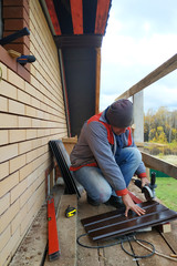 The master cuts the sheet metal on the drawn line to install the eaves.