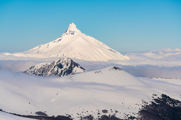 Snowy mountainous landscape, in the middle of the winter season, with the Puntiagudo volcano in the background surrounded by clouds