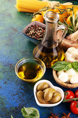 Italian food background with herbs and spices, vine tomatoes, basil, spaghetti, olives, parmesan, olive oil, garlic, peppercorns and fresh rosemary