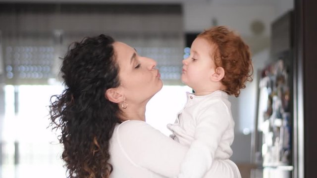 Slow motion 4K, two year old girl Beautiful Mother And her baby girl. Beauty Mom and her baby girl play together Kissing and hugging happy family. Mother's Day Joy.