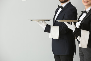 Male and female waiters on grey background