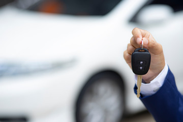 Close up of dealer giving key to new owner and shaking hands in auto show.