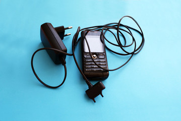 Old, mobile phone with charger, old technology.