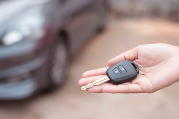 Close up of dealer giving key to new owner and shaking hands in auto show.