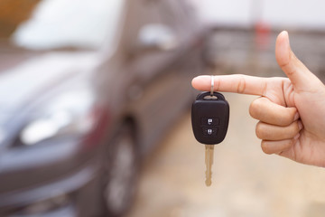Close up of dealer giving key to new owner and shaking hands in auto show.