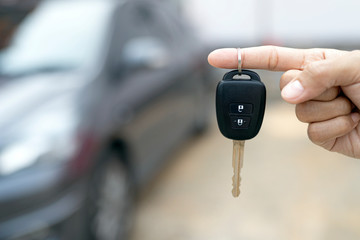 Close up of dealer giving key to new owner and shaking hands in auto show.