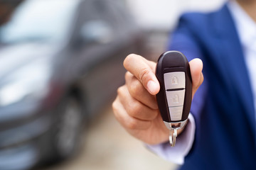 Close up of dealer giving key to new owner and shaking hands in auto show.