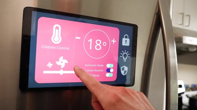 Man using Smart Refrigerator touch screen to control temprature of his Smart home in his kitchen