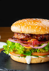 Juicy tasty burger with cheese, bacon and tomatoes. Cheeseburger close-up