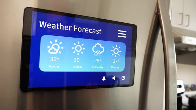 Man using his Smart Refregirator touch screen to see the weather forecast for the week in his kitchen at home