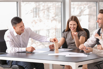 Team of business people playing jenga in office