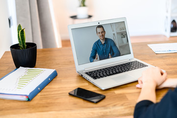 Close up a young man in smart casual shirt on the laptop screen, female hands beside laptop. Video...