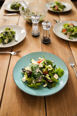 Wooden table with served green salad plates