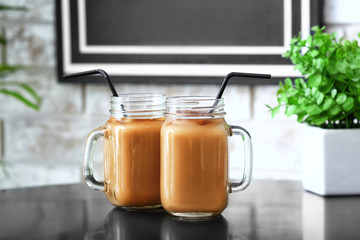 Mason jars of tasty iced coffee on table in cafe