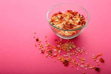Glass jar with yellow lentils on a pink background.
