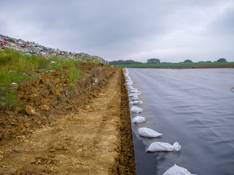 Working edge of a landfill expansion project with active landfill, clay cover, and HDPE synthetic liner in the same picture