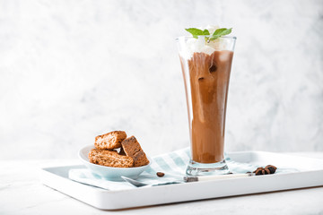 Glass of tasty iced coffee with cookies on table