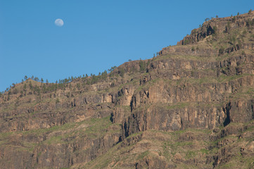 Moon over a cliff of the Pilancones Natural Park. San Bartolome de Tirajana. Gran Canaria. Canary Islands. Spain.