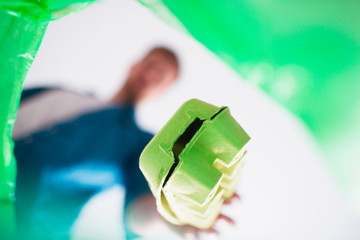 view from below. A man throws cardboard trash into a specially designed basket for cardboard trash