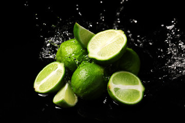 Fresh limes with water splashes on dark background