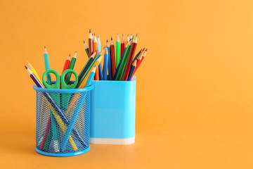 Holders with stationery on color background