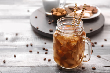 Mason jar of tasty iced coffee on table