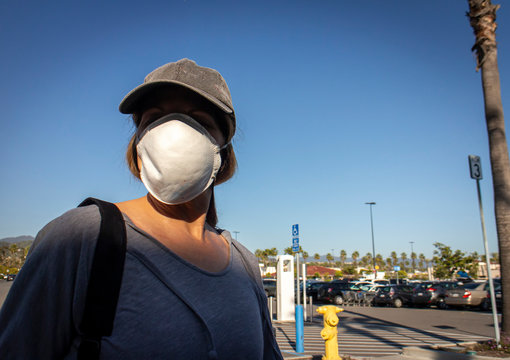 Close Up Of Woman  Wearing Face Mask With Baseball Cap In Store Parking Lot