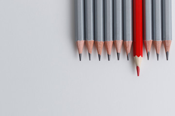 red pencil and gray pencils on a white paper background.