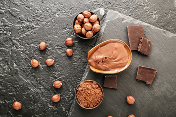 Bowls with tasty chocolate paste and hazelnuts on dark background