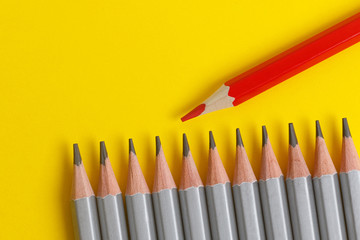 red pencil and gray pencils on a yellow paper background.