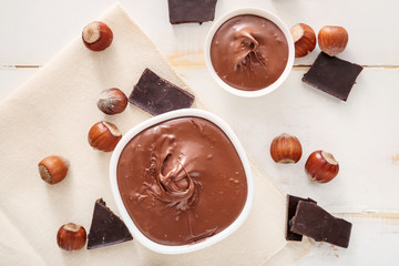 Bowls with tasty chocolate paste and hazelnuts on table