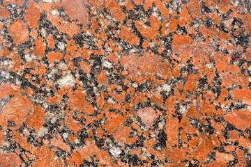 natural drawing of granitic surface with rich red hue, coarse-grained structure with small inclusions of various shades. Polished granite tile