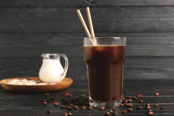 Glass of tasty cold coffee on table