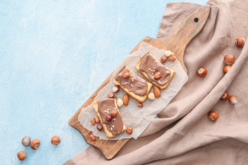 Board with fresh bread and chocolate paste on color background