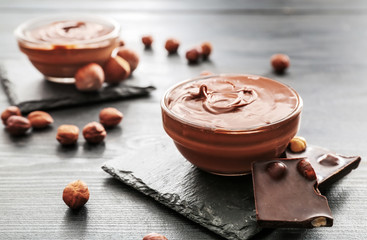 Bowl with tasty chocolate paste and hazelnuts on table