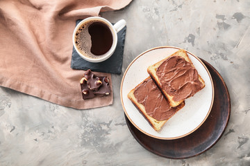 Plate with fresh bread, chocolate paste and cup of coffee on grunge background