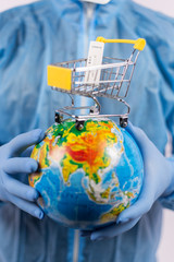 Hands in medical gloves holding a globe with a test for coronavirus, online shopping during a pandemic, vertical frame