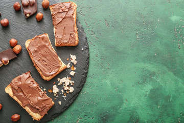 Slate plate with fresh bread and chocolate paste on color background