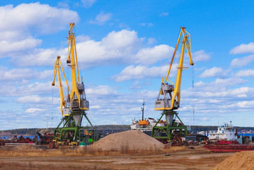 Fototapeta na wymiar Landscape photo of construction cranes on a background of blue sky, a beautiful picture of an industrial zone