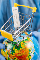 Hands in medical gloves holding a globe with a coronavirus test, online shopping during a pandemic, vertical frame, close-up