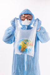 portrait of a man in a chemical protection suit, medical gloves, a mask and glasses holds a package with the planet Earth inside on a light background, close-up
