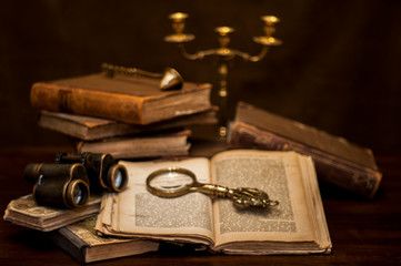 antique books, binoculars, a candelabra on a dark wood table
