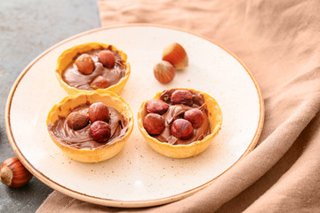 Plate with tartlets and tasty chocolate paste on grey background