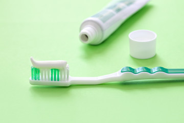 toothbrush on a green background with white toothpaste, morning brushing,